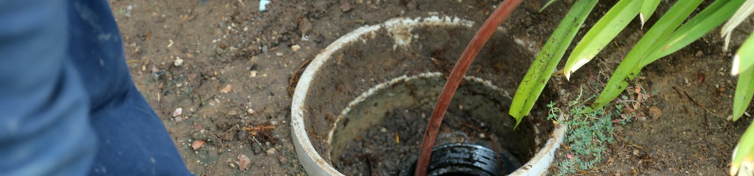 A cord going into a muddy hole in the ground